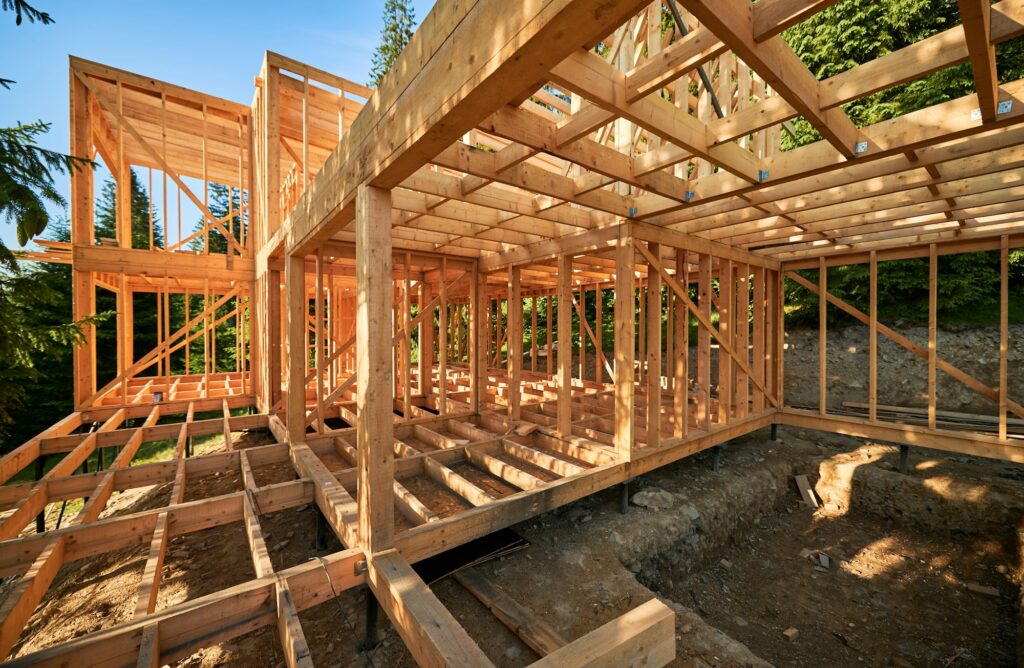 Wooden frame house under construction near forest.